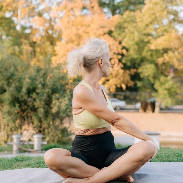 Person stretching peacefully outdoors during sunrise, symbolizing well-being and flexibility.